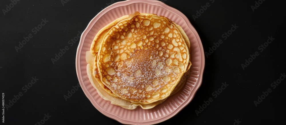 Poster top view of a homemade apple dutch pannekoek pancake served on a pink plate against a black backdrop