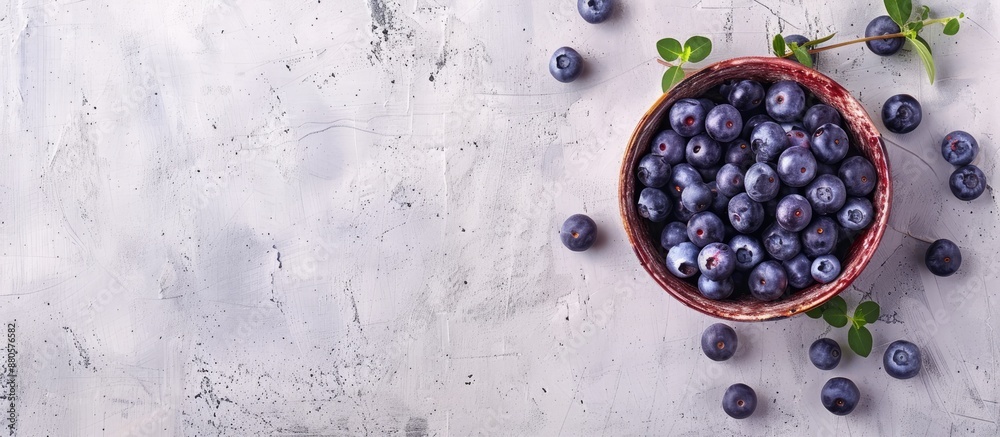 Poster top view of a bowl filled with blueberries on a wooden surface against a white concrete background w