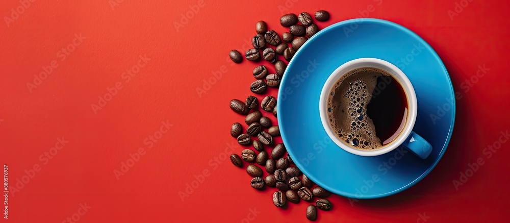 Poster top view of a blue cup of coffee with roasted coffee beans on a saucer against a red background offe
