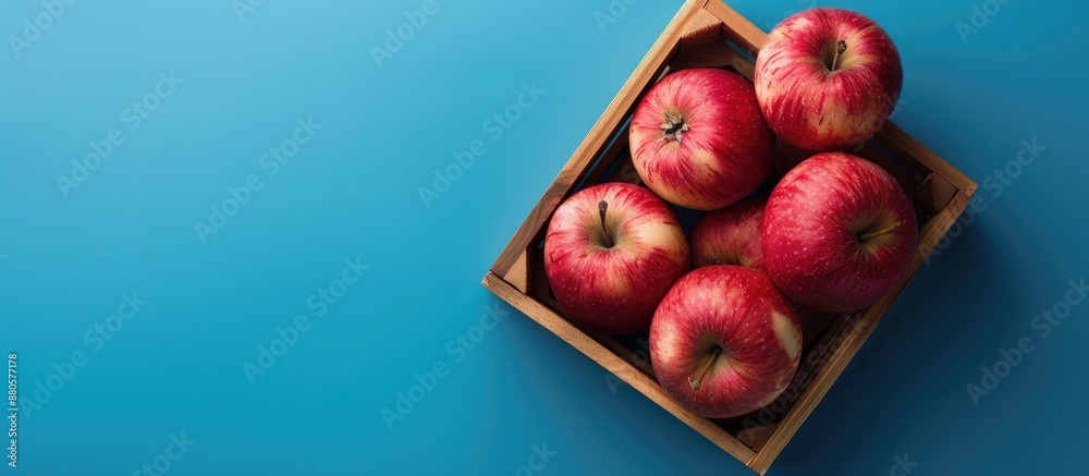 Poster pink apple beautifully arranged in a box against a blue background with copy space image