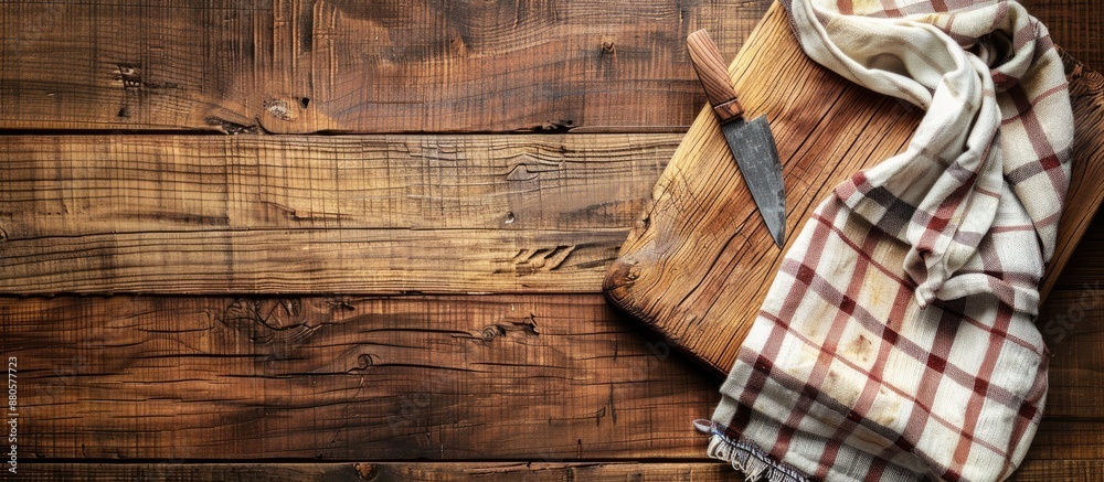 Poster top view of a cutting board on a wooden kitchen table with a towel underneath creating a rustic kitc