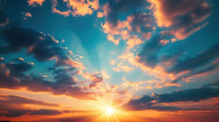 Beautiful sunset with rays of sun breaking through clouds sky with orange blue colors wide view from below