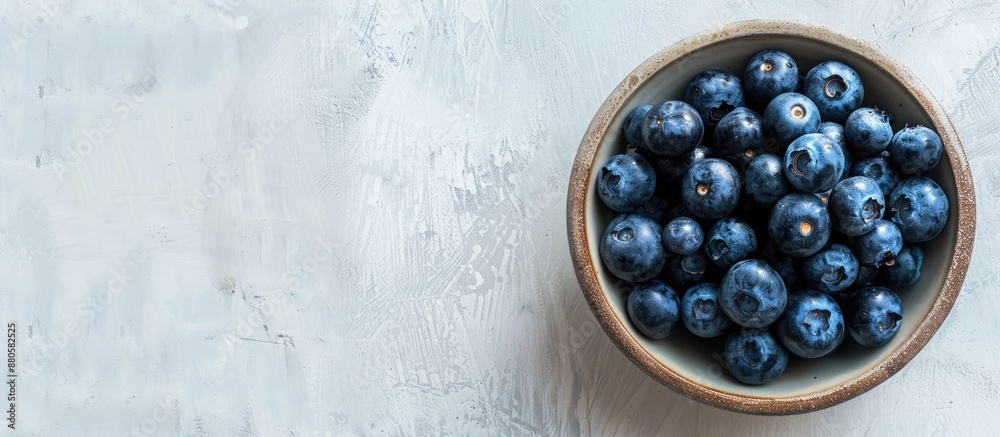 Poster top view of a bowl filled with blueberries on a wooden surface against a white concrete background w