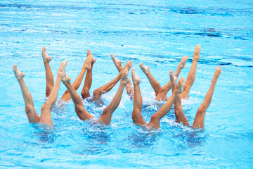 Artistic swimming team performing synchronized legs movement in swimming pool
