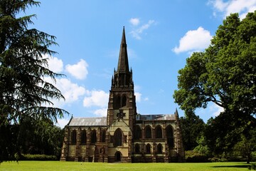 silhouette of a beautiful old Anglican church against a background of green trees and a blue summer sky