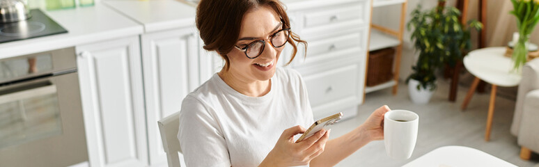 Middle aged woman sitting at table, engrossed in cell phone.