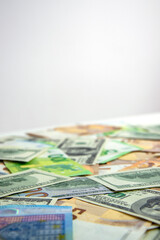 A close-up shot of a pile of US dollar and euro banknotes scattered on a white surface