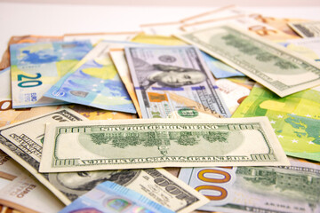 A close-up photograph showing a collection of US Dollar and Euro banknotes strewn across a white surface