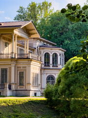 Fototapeta premium A beautifully preserved historic mansion in St. Petersburg, showcasing intricate architectural details and set against a backdrop of lush greenery. Perfect for themes of heritage, architecture, and