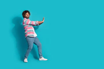 Photo of cheerful nice funny man wear trendy striped clothes hold empty space isolated on cyan color background