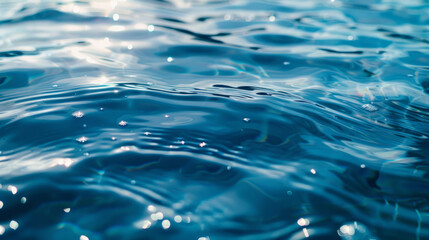 Mesmerizing blue water surface caught in a blurry close-up. The reflections from sunlight create an abstract background. Overhead shot of sparkling blue water, captured in an abstract splashy moment.