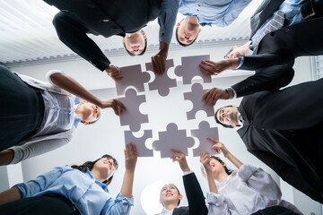Multiethnic business people holding jigsaw pieces and merge them together as effective solution...