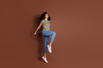 Full length photo of adorable lovely girl wear khaki t-shirt jumping high empty space isolated...