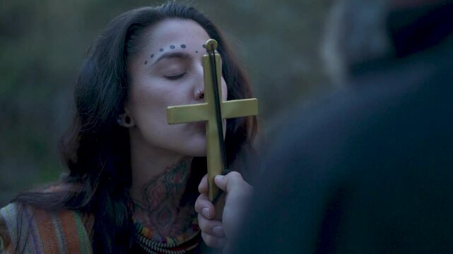 Indigenous woman kisses a Catholic cross during the conquest of America