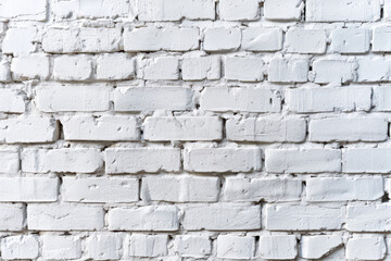 A textured white brick wall with uneven, rough surfaces and old weathered look, suitable for backgrounds and architectural themes.