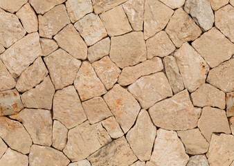 Seamless photography close-up view of a dry stone wall made of various stones arranged in a geometric pattern. In Mallorca