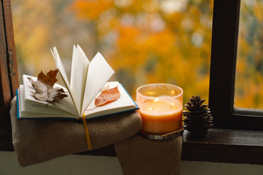Sweet Home. Still life details in home on a wooden window. Sweater, candle and autumn decor. Autumn home decor. Cozy fall mood. Cozy autumn or winter concept.