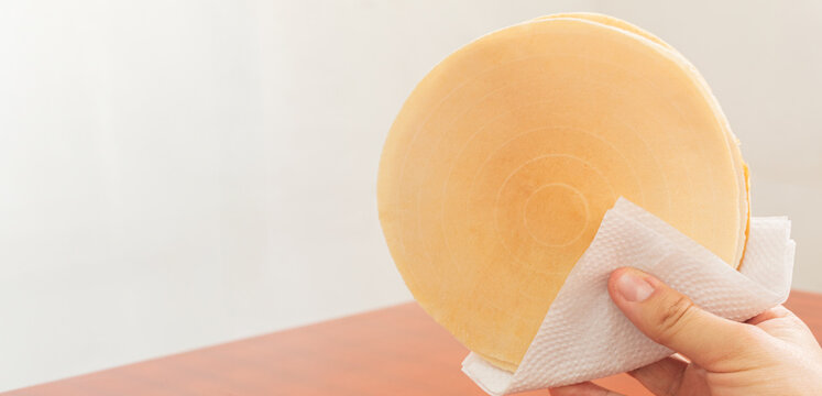 A hand using a napkin to hold a oblea filled with arequipe. Colombian dessert. Image with copy space.