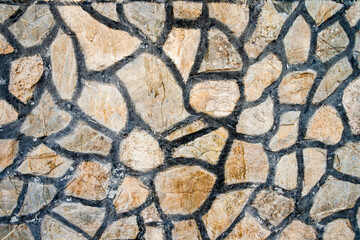Close up of a stone wall with irregularly shaped stones and dark mortar lines.