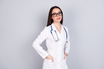 Photo of charming adorable woman surgeon wear white doctor uniform hand in pockets isolated on grey color background