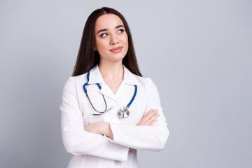 Portrait of qualified doctor woman folded hands look empty space white coat isolated on grey color background