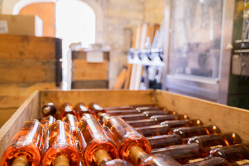 The winery cellar has neat rows of wine bottles in a wooden crate, offering a charming and rustic atmosphere