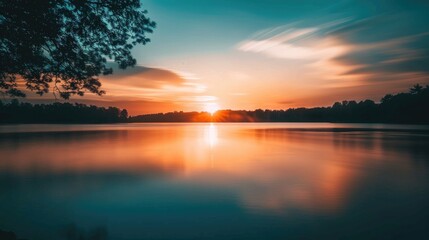 Obraz premium Stunning sunset over a lake with a silhouette foreground soft focus from a long exposure shot Perfect nature background