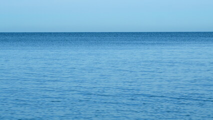 Fototapeta premium Quiet Seascape. Calming Waves Of The Sea Or Ocean During A Warm Sunny Day With A Blue Cloudless Sky. Real time.