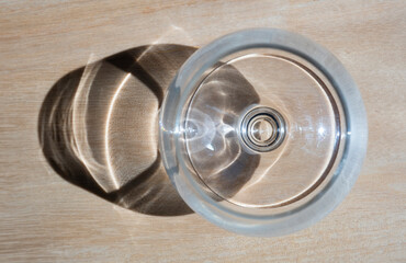 Empty wine or shot glass seen from above with shadow on wooden background