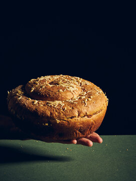 a hand holding a bread on a green surface with black background