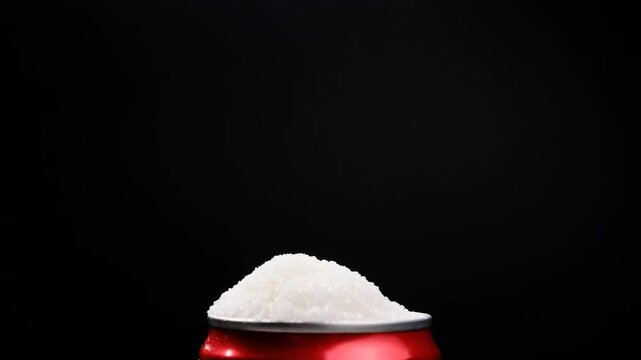A can of soda with white sugar poured onto a black background, showing an example of how harmful sugar is and how we all eat too much sugar in a healthy eating concept.
