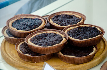 Delicious and fresh desserts in the form of tartlets on display behind glass