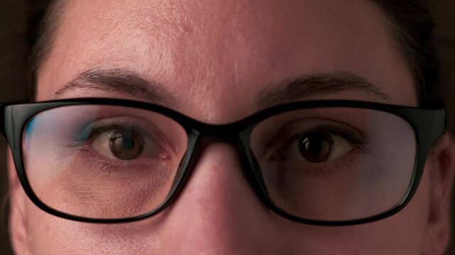 Close-up of a young adult Caucasian brunette woman looking at the camera and putting on glasses. Ophthalmology and vision impairment concept