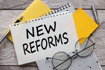 New Reforms text on a sheet of paper on a yellow notepad