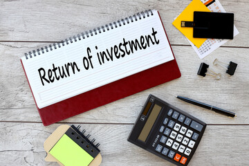 Flash drive calculator and stickers near the diary with text Roi Return On Investment Analysis Finance Concept.