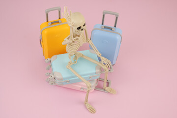 Skeleton with many suitcases on pink background. Waiting tourist concept.