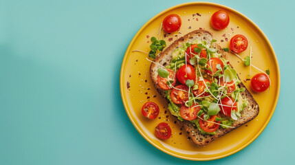 Avocado toast with cherry tomatoes and microgreens on a yellow plate against turquoise background