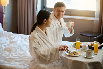 Couple having breakfast in hotel room in morning