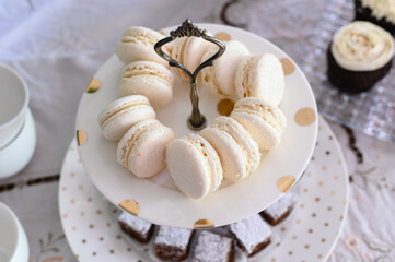 Vanilla macarons arranged elegantly on a white plate with gold detailing, surrounded by other