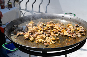 Chicken and pork meat cooking on large paella pan at summer outdoor party