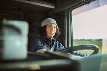 Mature female truck driver at the wheel on the road