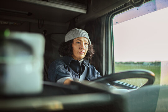 Mature female truck driver at the wheel on the road