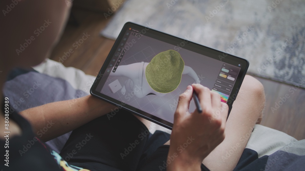 Poster boy with digital stylus and tablet in hands sits at home, creates 3d models. focused teenager draws 