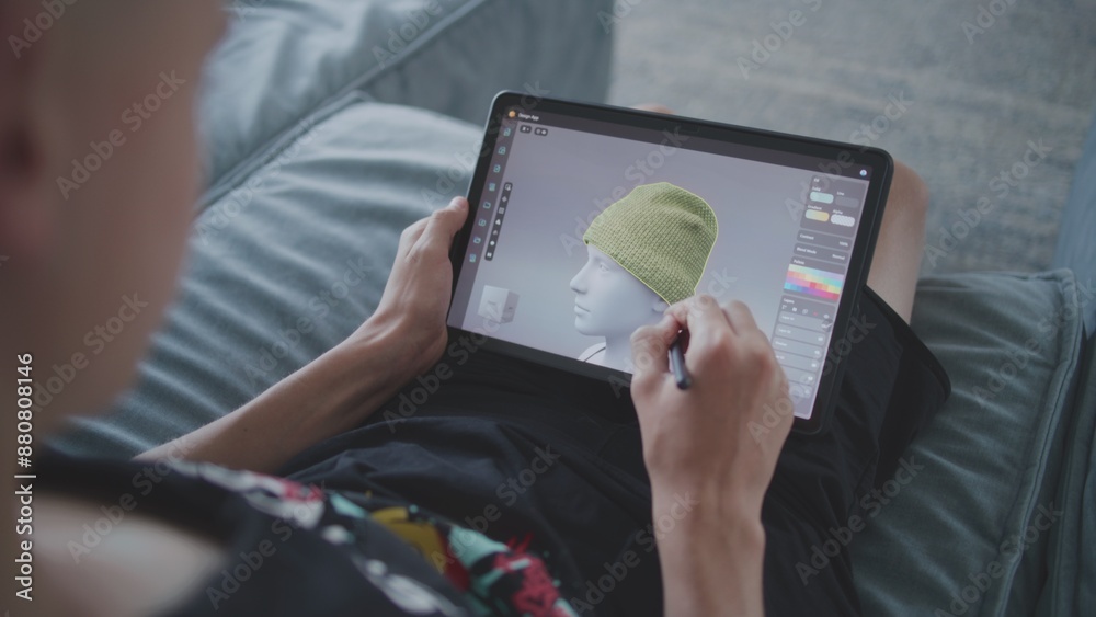 Aufkleber focused teenager with digital pencil and tablet in hands sits in room, draws 3d model. boy creates n