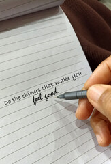 Life inspirational motivational quote - Do the things that make you feel good. With person holding pen pointing on text message on white lines paper. Self love care concept. Happiness.