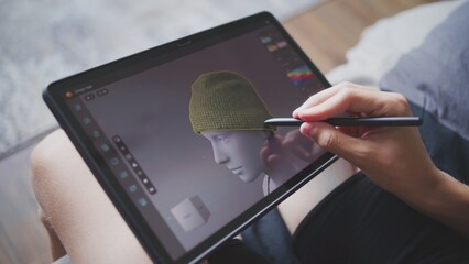 Boy with digital stylus and tablet in hands sits at home, creates 3d models. Focused teenager draws clothes for game character using 3d modeling program. Development and game design concept. Close up. © Framestock