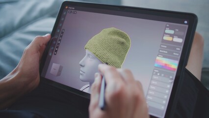 Focused teenager with digital pencil and tablet in hands sits in room, draws 3d model. Boy creates...