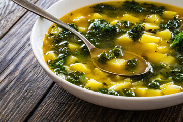 Portuguese green soup - Caldo Verde.  Potato and kale soup served in white bowl on wooden table