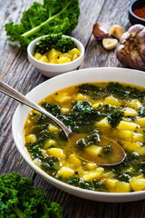 Portuguese green soup - Caldo Verde.  Potato and kale soup served in white bowl on wooden table