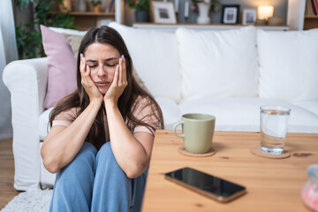 Young depressed sad anxious and worried woman sitting alone on the floor waiting for phone call...